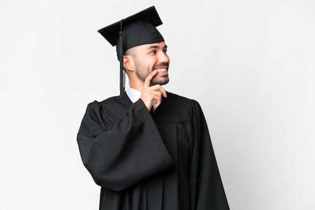 Young university graduate man over isolated white background thinking an idea while looking up