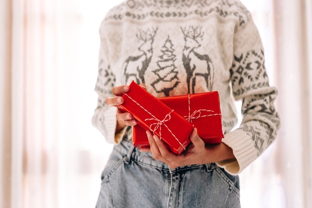 Young unrecognizable woman holds in a gift box in red paper.