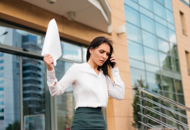 Young upset business woman is wearing blouse and a skirt leaving the business center and going down the stairs