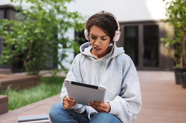 Young upset lady in headphones sitting and amazedly 