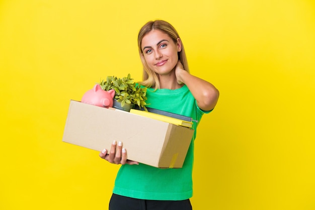 Young Uruguayan girl making a move while picking up a box full of things isolated on yellow background laughing