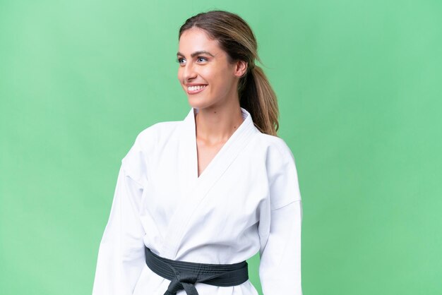 Young Uruguayan woman doing karate over isolated background looking side