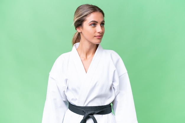 Young Uruguayan woman doing karate over isolated background looking to the side