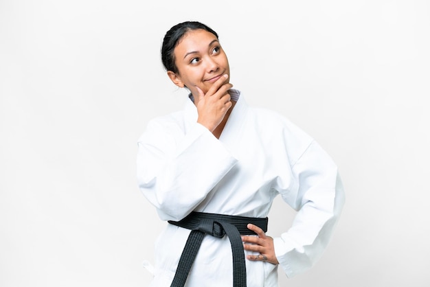 Young Uruguayan woman doing karate over isolated white background looking up while smiling