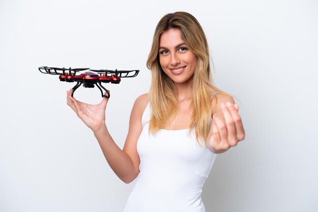 Young Uruguayan woman holding a drone isolated on white background making money gesture