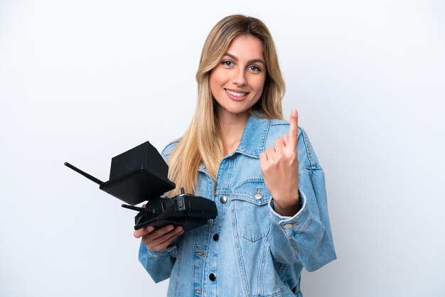 Young Uruguayan woman holding a drone remote control isolated on white background doing coming gesture