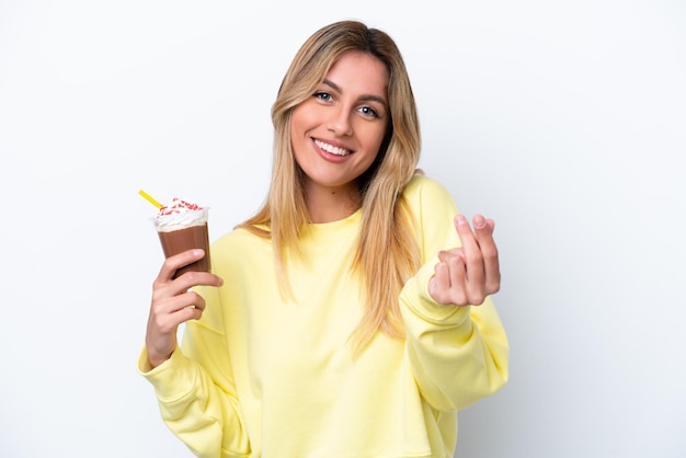 Young Uruguayan woman holding Frappuccino isolated on white background making money gesture