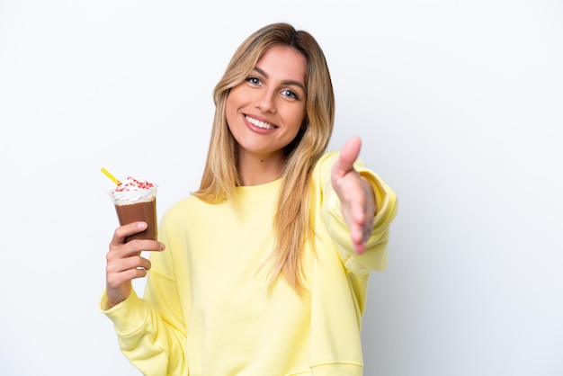 Young Uruguayan woman holding Frappuccino isolated on white background shaking hands for closing a good deal