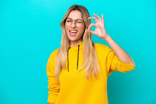 Young Uruguayan woman isolated on blue background showing ok sign with fingers