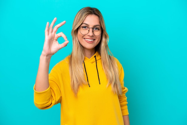 Young Uruguayan woman isolated on blue background showing ok sign with fingers