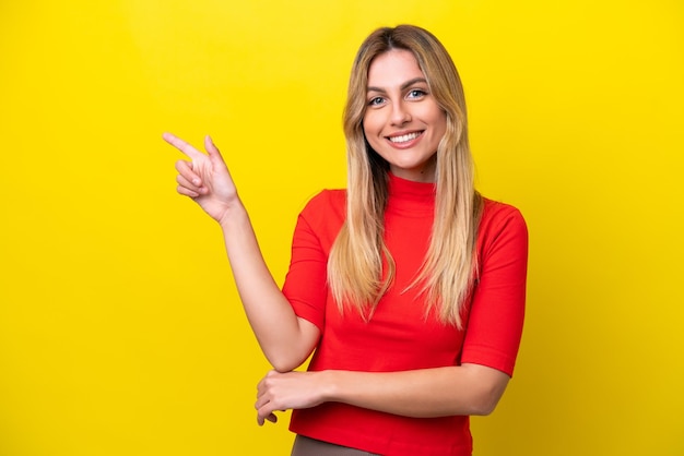 Young Uruguayan woman isolated on yellow background happy and pointing up