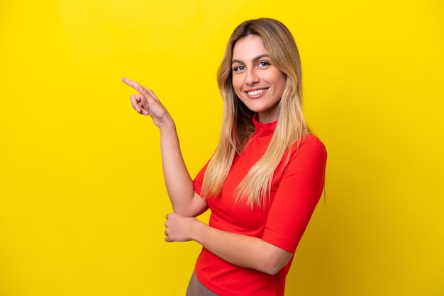 Young Uruguayan woman isolated on yellow background pointing finger to the side