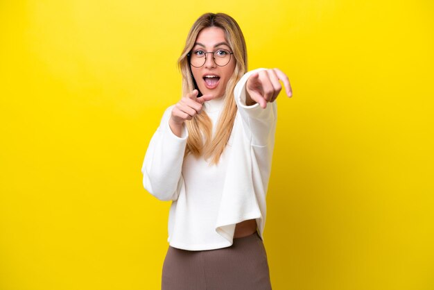 Young Uruguayan woman isolated on yellow background surprised and pointing front