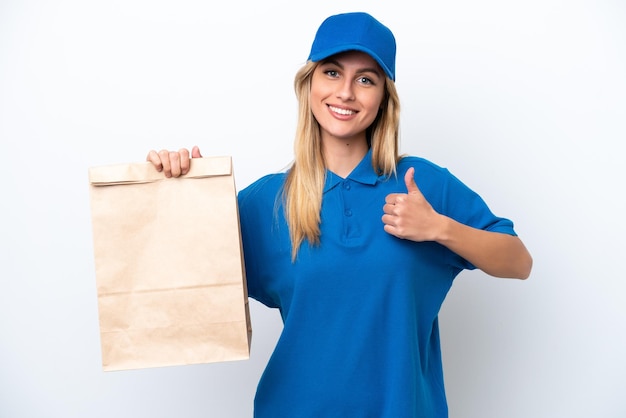 Young Uruguayan woman taking a bag of takeaway food isolated on white background giving a thumbs up gesture