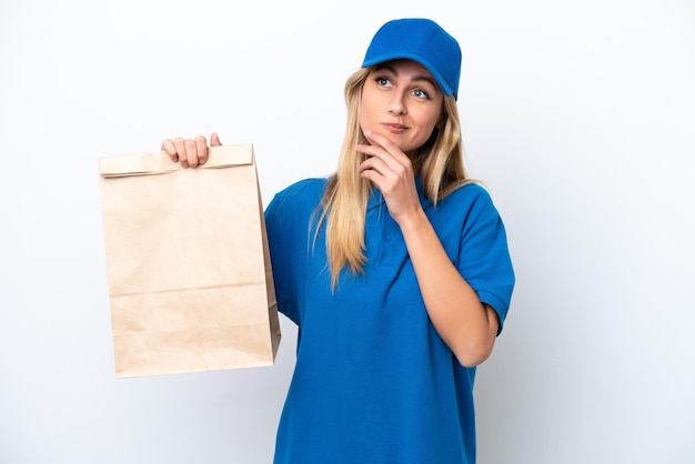 Young Uruguayan woman taking a bag of takeaway food isolated on white background and looking up