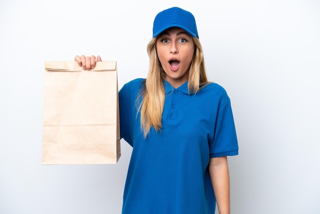 Young Uruguayan woman taking a bag of takeaway food isolated on white background with surprise facial expression