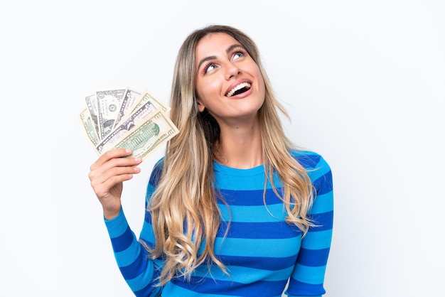 Young Uruguayan woman taking a lot of money isolated on white background laughing