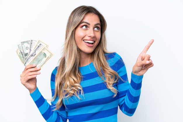 Young Uruguayan woman taking a lot of money isolated on white background pointing up a great idea