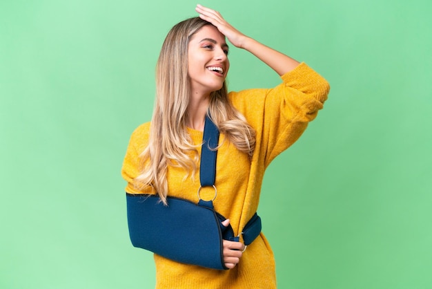 Young Uruguayan woman with broken arm and wearing a sling over isolated background smiling a lot