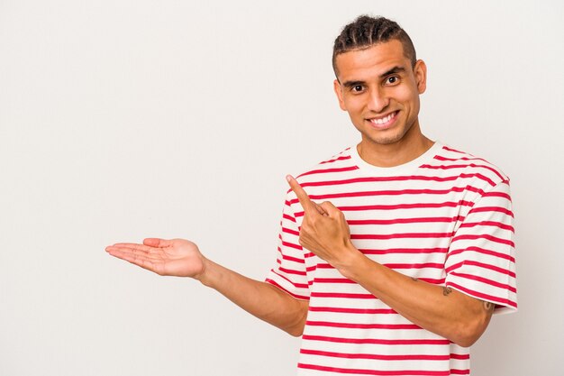 Young venezuelan man isolated on white background excited holding a copy space on palm.