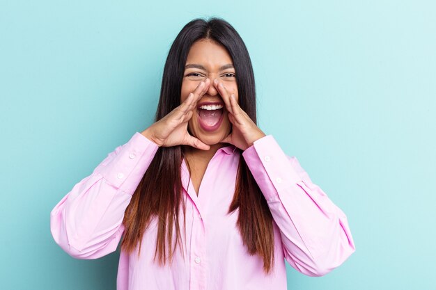 Young Venezuelan woman isolated on blue background shouting excited to front.