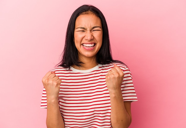 Young Venezuelan woman isolated on pink background cheering carefree and excited. Victory concept.