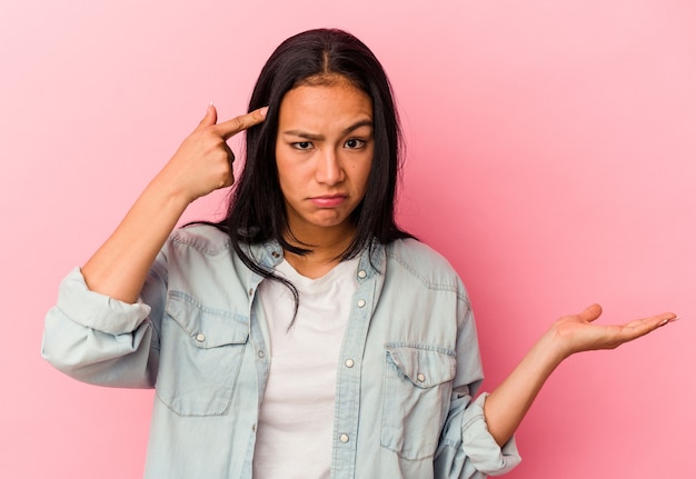 Young Venezuelan woman isolated on pink background showing a disappointment gesture with forefinger.