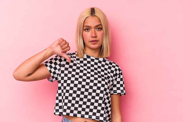 Young venezuelan woman isolated on pink wall showing a dislike gesture, thumbs down