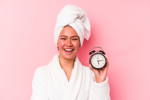 Young venezuelan woman late for work isolated on pink background laughing and having fun.