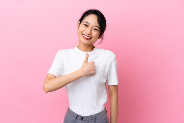 Young Vietnamese woman isolated on pink background giving a thumbs up gesture