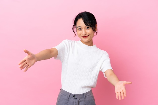 Young Vietnamese woman isolated on pink background presenting and inviting to come with hand