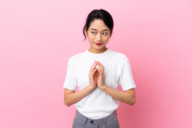 Young Vietnamese woman isolated on pink background scheming something