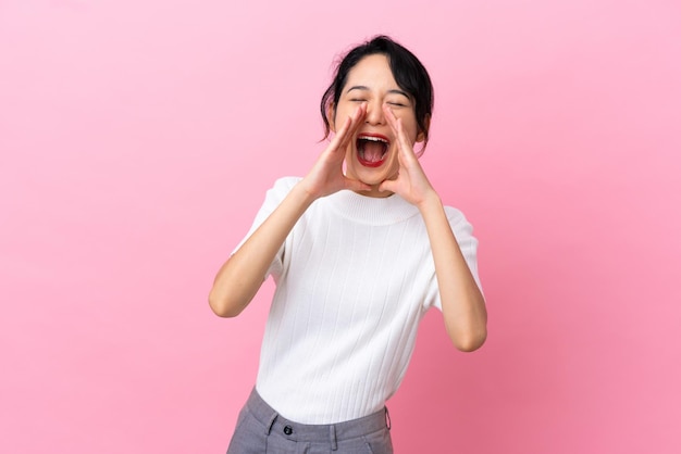 Young Vietnamese woman isolated on pink background shouting and announcing something