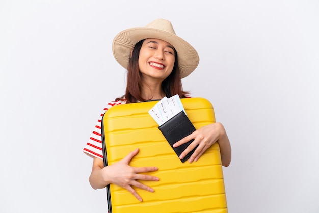 Young Vietnamese woman isolated on white background in vacation with suitcase and passport