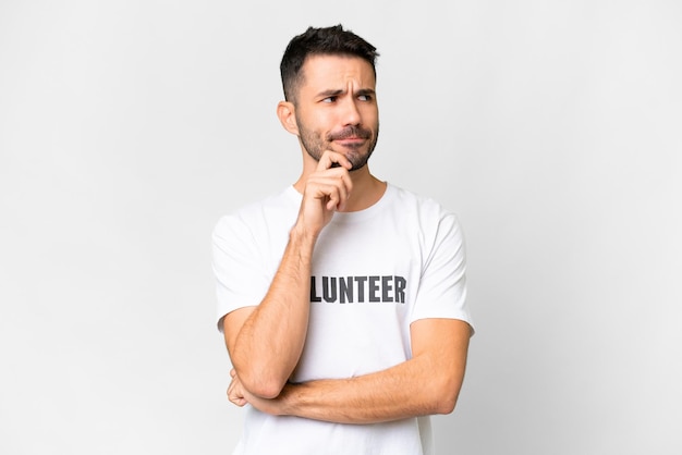 Young volunteer caucasian man over isolated white background having doubts and thinking