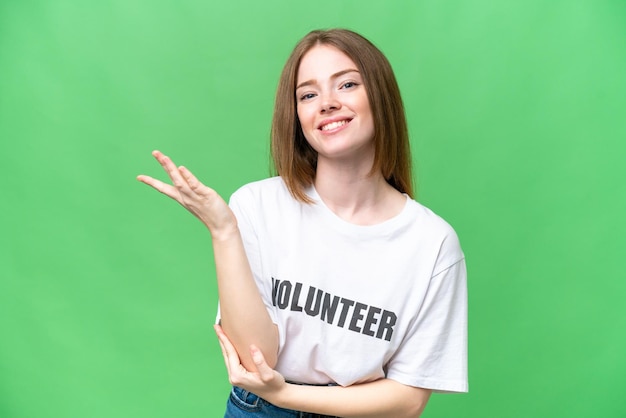 Young volunteer woman over isolated chroma key background extending hands to the side for inviting to come