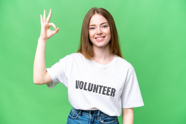 Young volunteer woman over isolated chroma key background showing ok sign with fingers