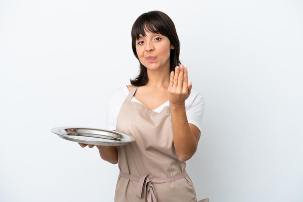 Young waitress with tray isolated on white background inviting to come with hand Happy that you came