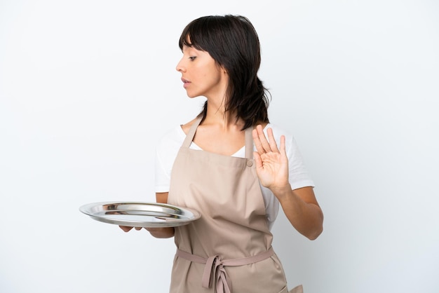 Young waitress with tray isolated on white background making stop gesture and disappointed