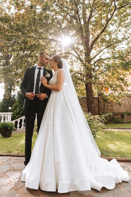 Young wedding couple enjoying romantic moments outdoors in autumn park under sunlight