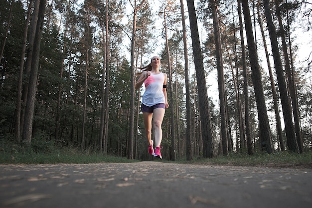 Young white redhead skinny girl running in the summer forest.