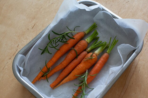 Young whole carrot with greens in baking tray