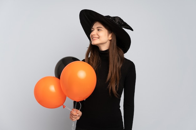 Young witch holding black and orange air balloons