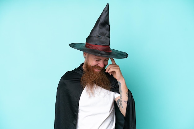 Young wizard in halloween isolated on blue background laughing