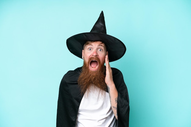 Young wizard in halloween isolated on blue background with surprise and shocked facial expression