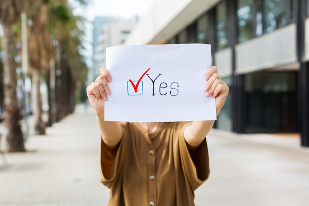 Young woman, activist calls to vote holding in hands paper with statement YES. Political activism, election process, active life positions concept. President, constitution elections.