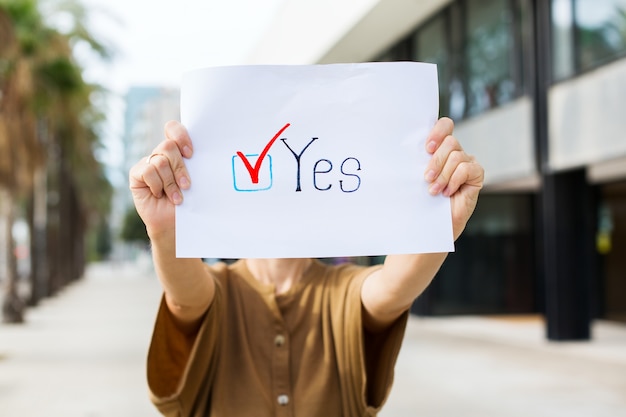 Young woman, activist calls to vote holding in hands paper with statement YES. Political activism, election process, active life positions concept. President, constitution elections.