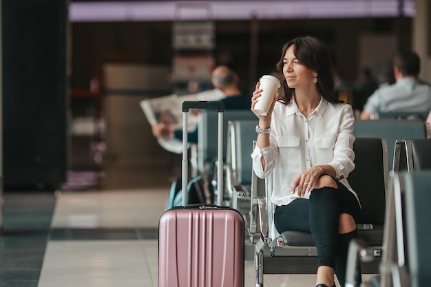 Young woman in an airport lounge waiting for flight aircraft