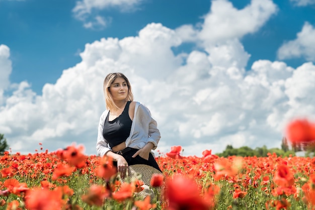 Young woman alone at poppy in field summer day