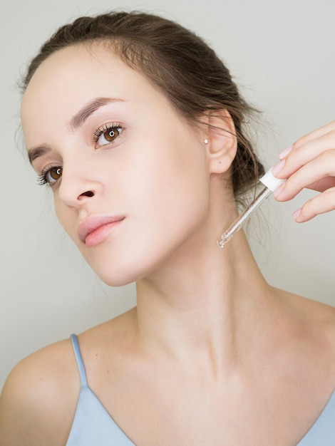 young woman applies cosmetic oil to the neck